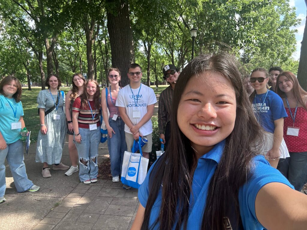 Students attending orientation posing for a photo at the blue horseshoe at MTSU with their Student Orientation Assistant.