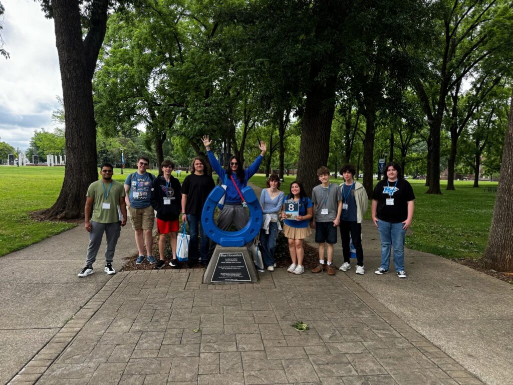 Students in Group 8 of orientation posing for a photo at the blue horseshoe at MTSU with their Student Orientation Assistant.