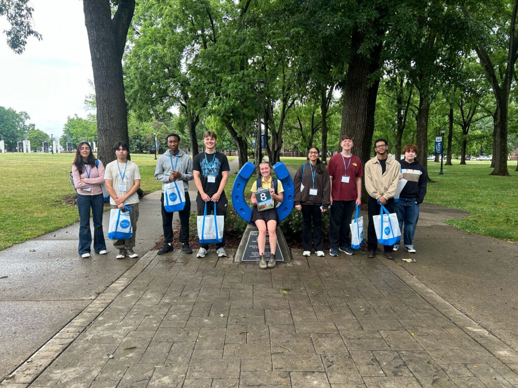 Students in Group 8 of orientation posing for a photo at the blue horseshoe at MTSU with their Student Orientation Assistant.