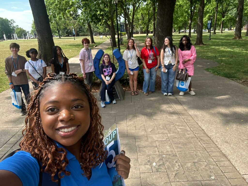 Students attending orientation posing for a photo at the blue horseshoe at MTSU with their Student Orientation Assistant.