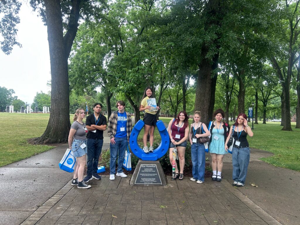 Students in Group 24 of orientation posing for a photo at the blue horseshoe at MTSU with their Student Orientation Assistant.