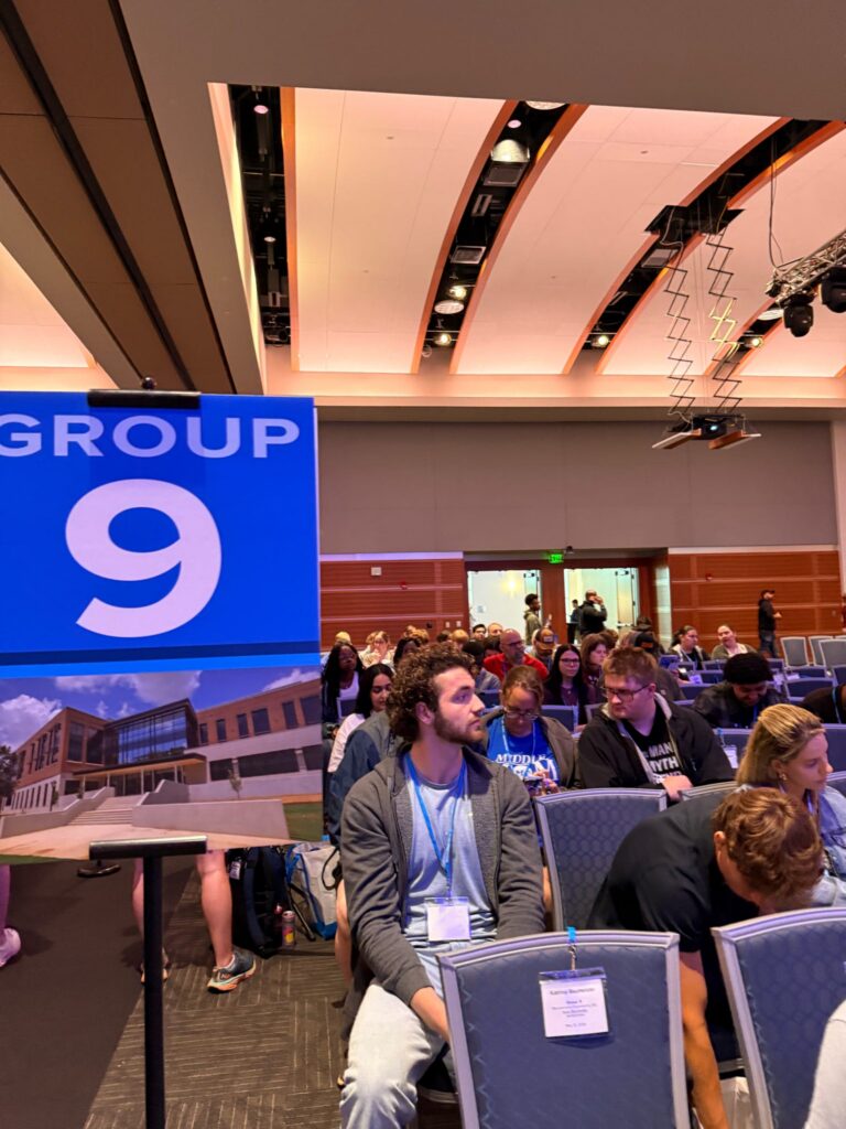 Students and guests attending New to Blue Orientation sitting in the Student Union near the Group 9 sign.