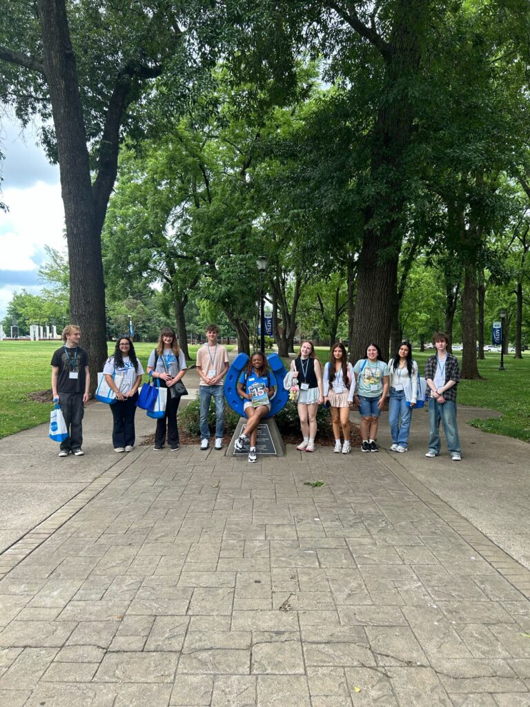 Students in Group 15 of orientation posing for a photo at the blue horseshoe at MTSU with their Student Orientation Assistant.