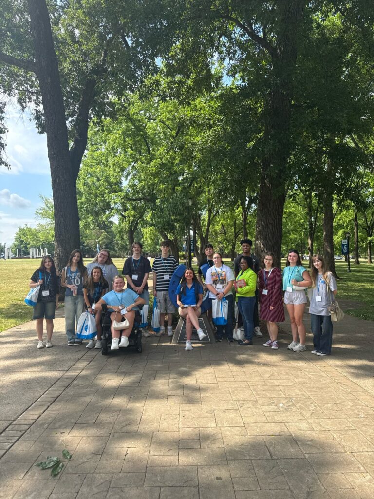 Students attending orientation posing for a photo at the blue horseshoe at MTSU with their Student Orientation Assistant.