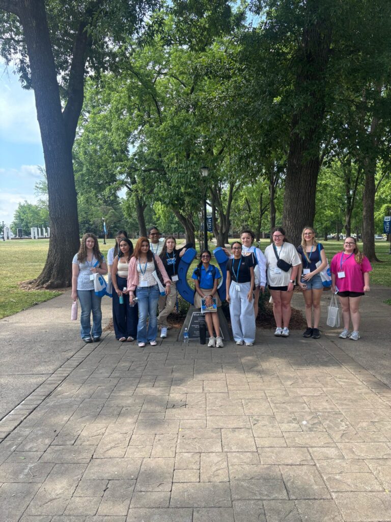 Students posing for a photo at the blue horseshoe at MTSU with their Student Orientation Assistant.