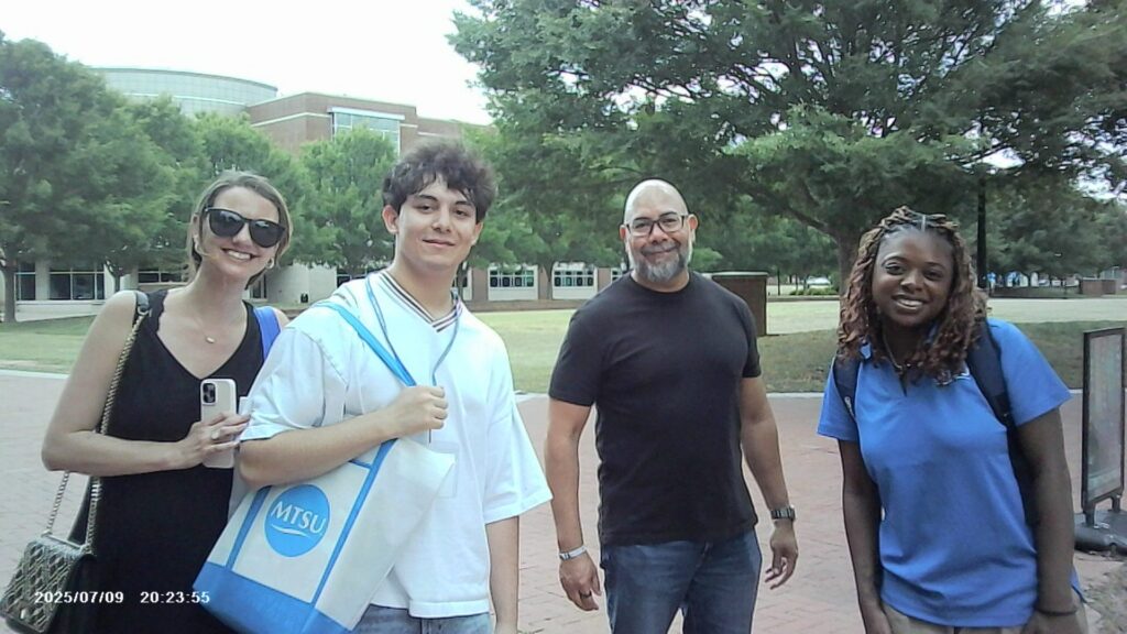A student attending New to Blue Orientation with their family and guests, posed beside their Student Orientation Assitant.