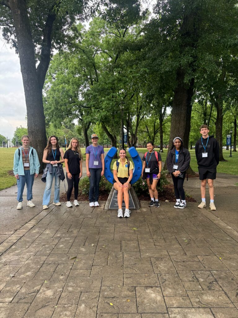 Students attending orientation posing for a photo at the blue horseshoe at MTSU with their Student Orientation Assistant.