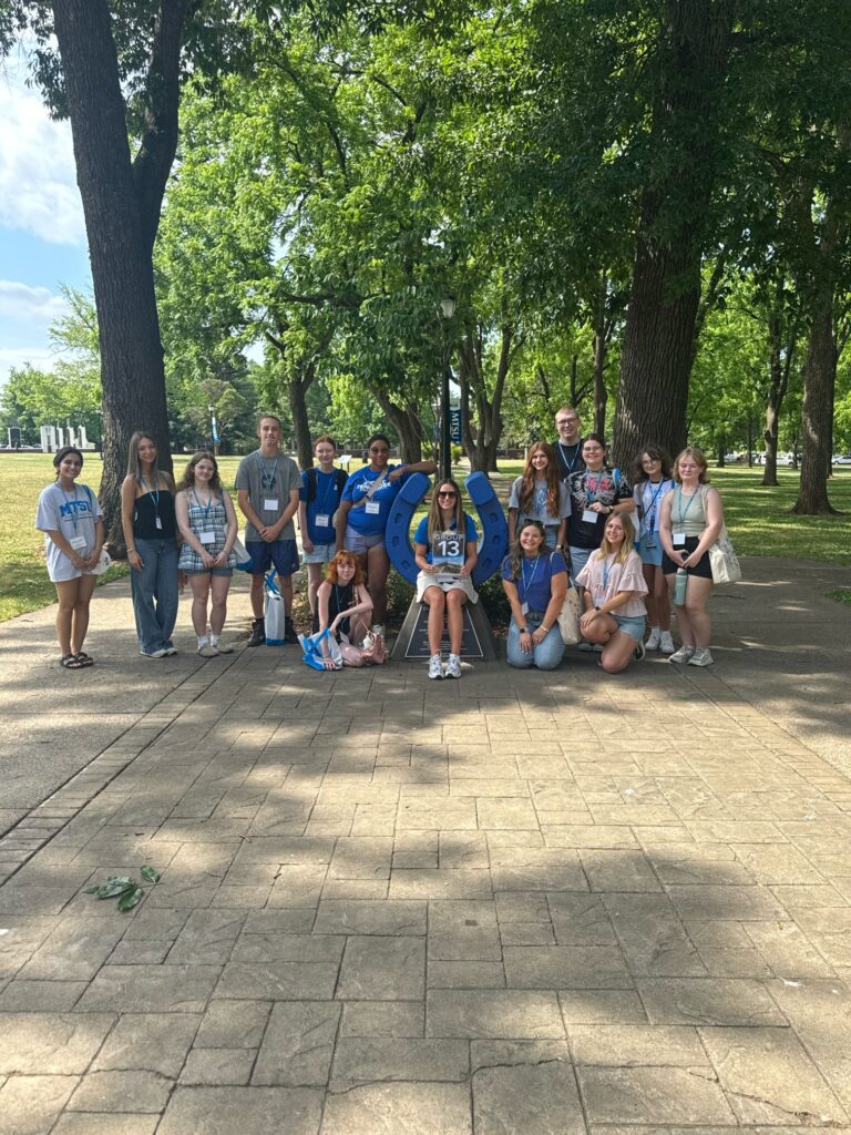 Students in Group 13 of orientation posing for a photo at the blue horseshoe at MTSU with their Student Orientation Assistant.
