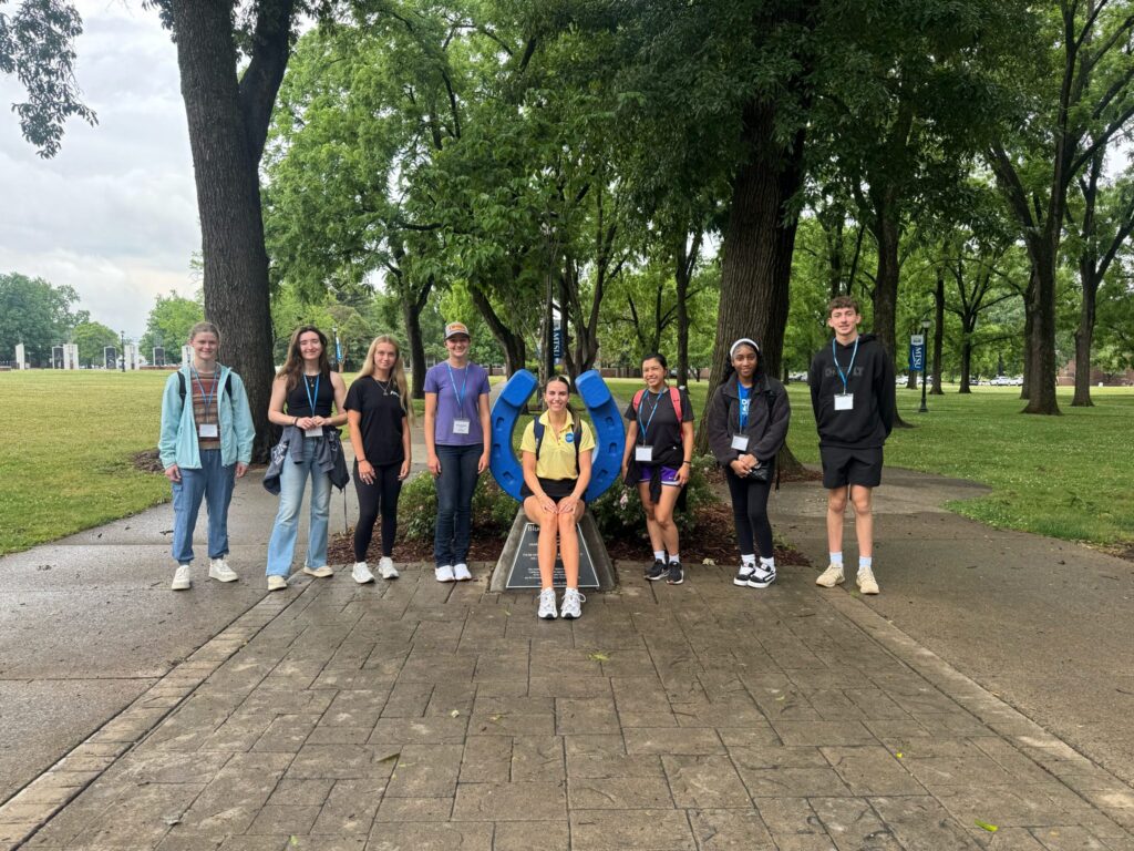 Students attending orientation posing for a photo at the blue horseshoe at MTSU with their Student Orientation Assistant.