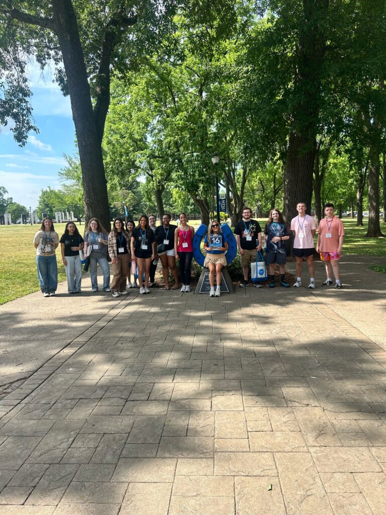 Students in Group 16 of orientation posing for a photo at the blue horseshoe at MTSU with their Student Orientation Assistant.