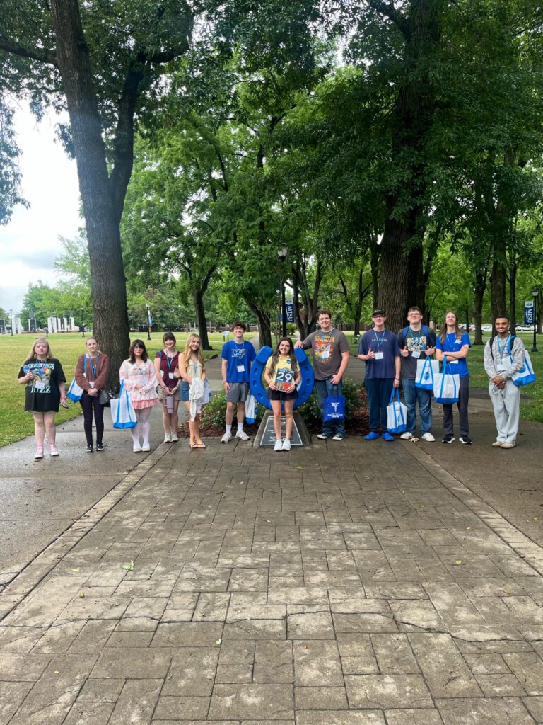 Students in Group 29 of orientation posing for a photo at the blue horseshoe at MTSU with their Student Orientation Assistant.