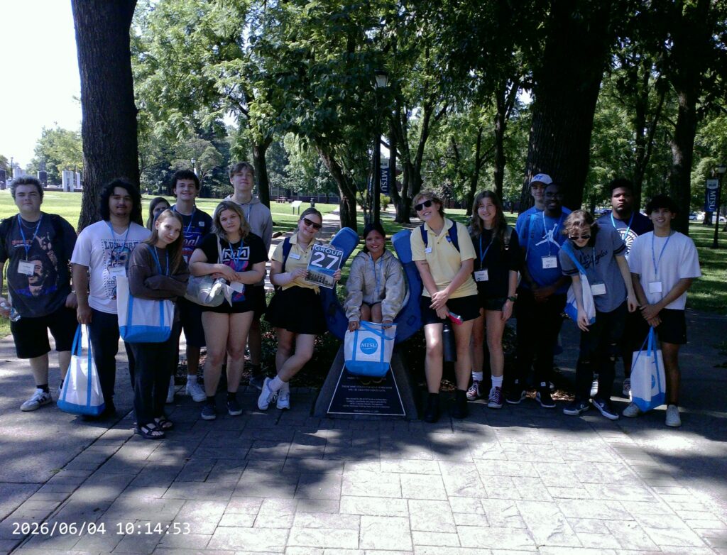 Students in Group 27 of orientation posing for a photo at the blue horseshoe at MTSU with their Student Orientation Assistant.