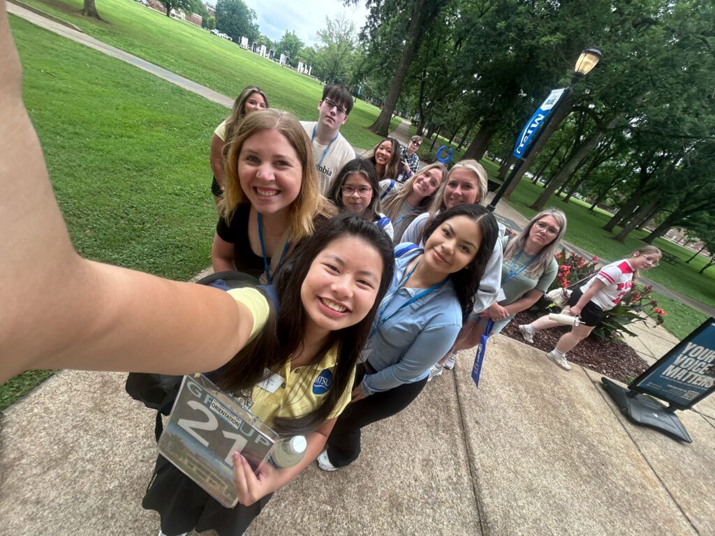 Students in Group 21 of orientation posing for a photo in Walnut Grove at MTSU with their Student Orientation Assistant.