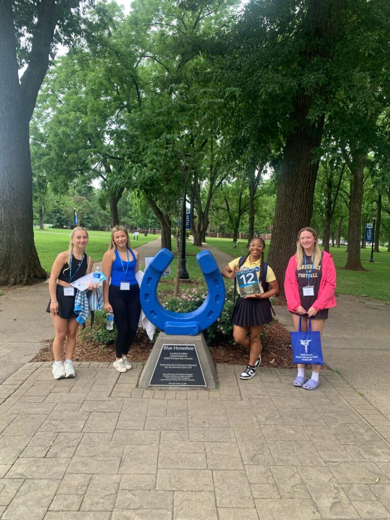 Students in Group 12 of orientation posing for a photo at the blue horseshoe at MTSU with their Student Orientation Assistant.