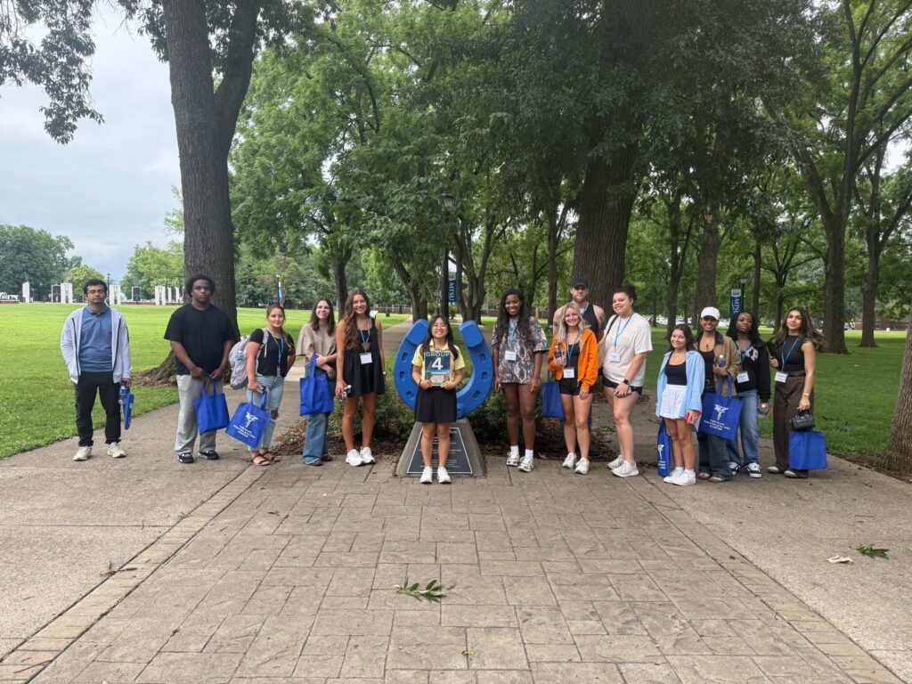Students in Group 4 of orientation posing for a photo at the blue horseshoe at MTSU with their Student Orientation Assistant.