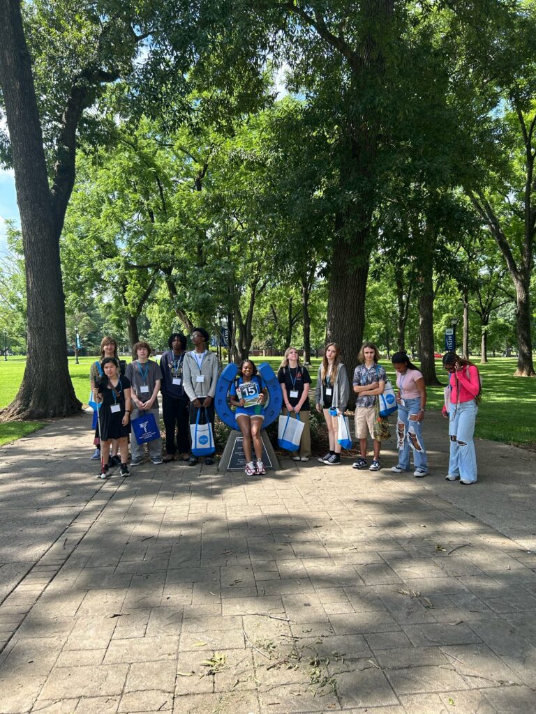 Students in Group 15 of orientation posing for a photo at the blue horseshoe at MTSU with their Student Orientation Assistant.
