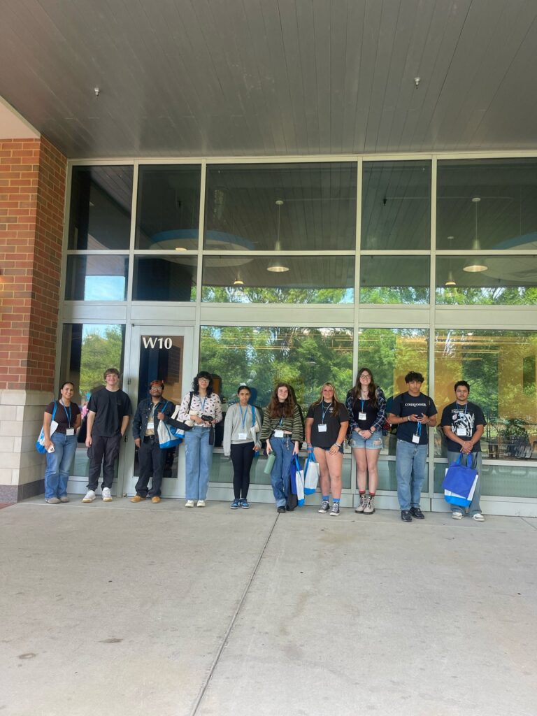 Students lined up at a campus building taking a group photo