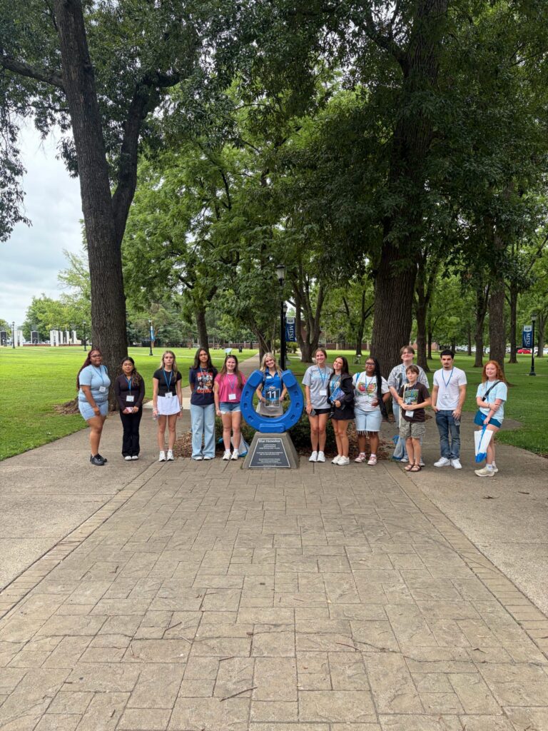 Students in Group 11 of orientation posing for a photo at the blue horseshoe at MTSU with their Student Orientation Assistant.