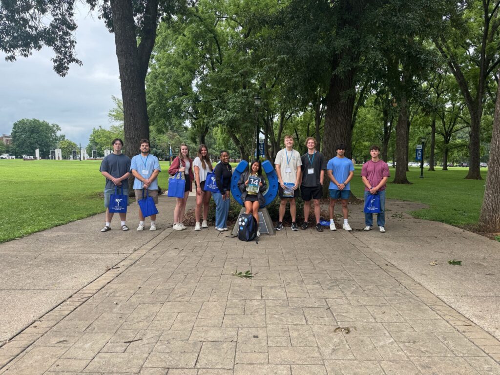 Students in Group 14 of orientation posing for a photo at the blue horseshoe at MTSU with their Student Orientation Assistant.
