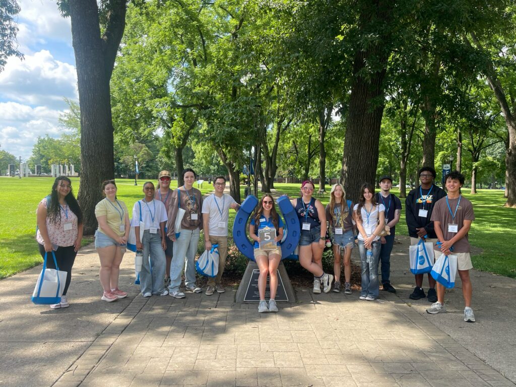 Students in Group 5 of orientation posing for a photo at the blue horseshoe at MTSU with their Student Orientation Assistant.