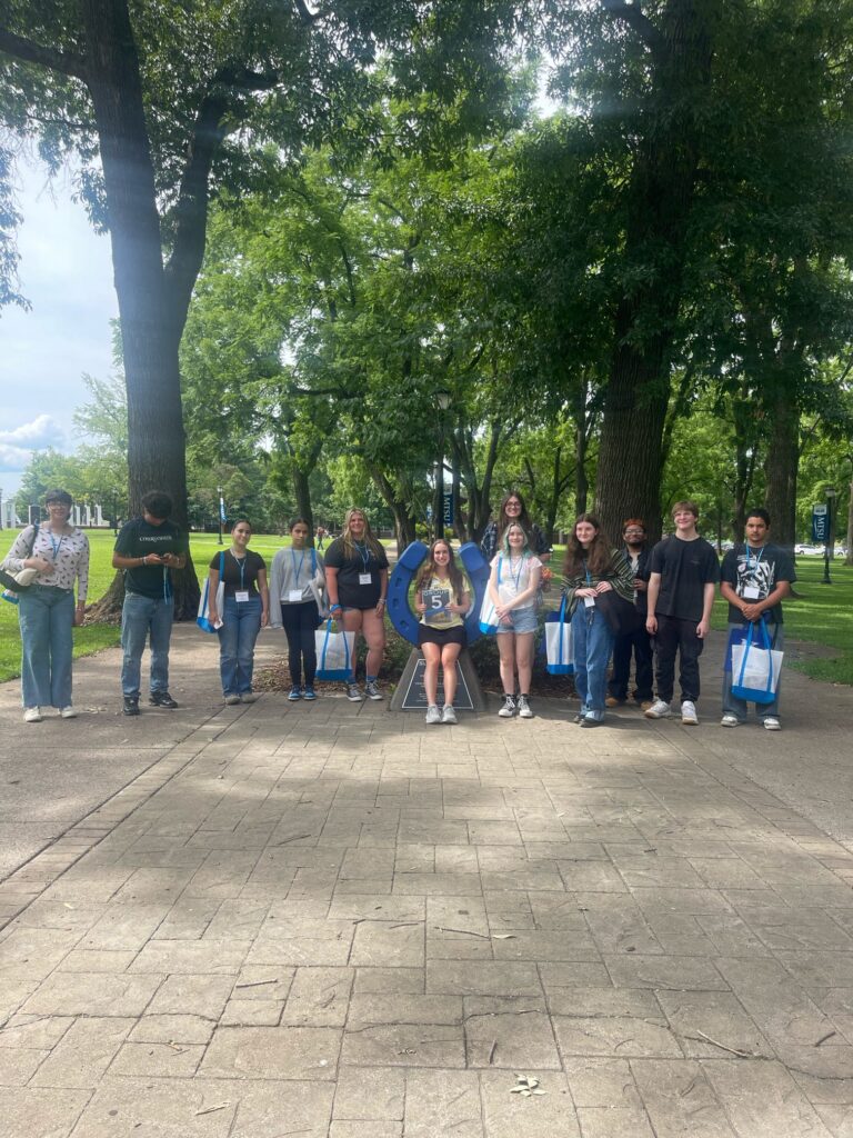 Students in Group 5 of orientation posing for a photo at the blue horseshoe at MTSU with their Student Orientation Assistant.