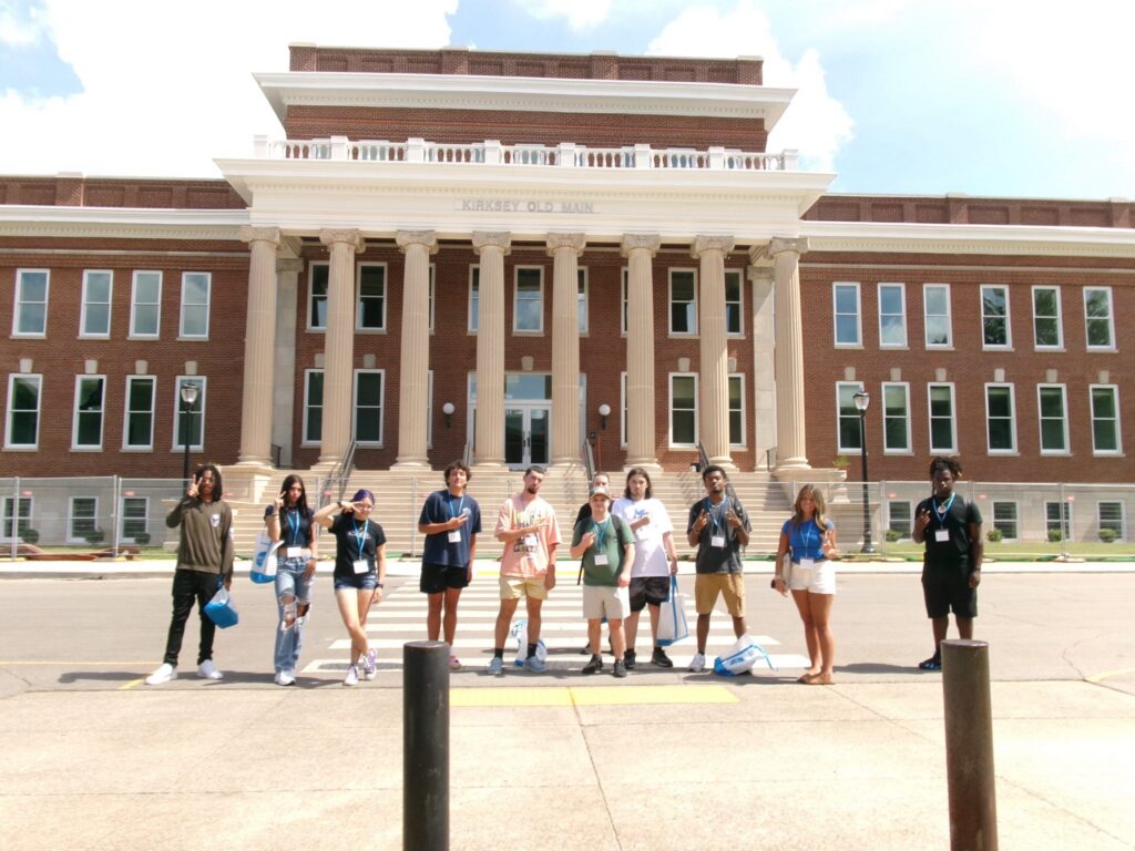 Students attending orientation posing outside the renovated Kirksey Old Main.