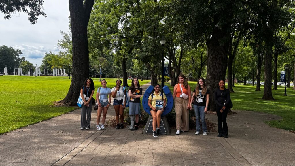 Students in Group 25 of orientation posing for a photo at the blue horseshoe at MTSU with their Student Orientation Assistant.
