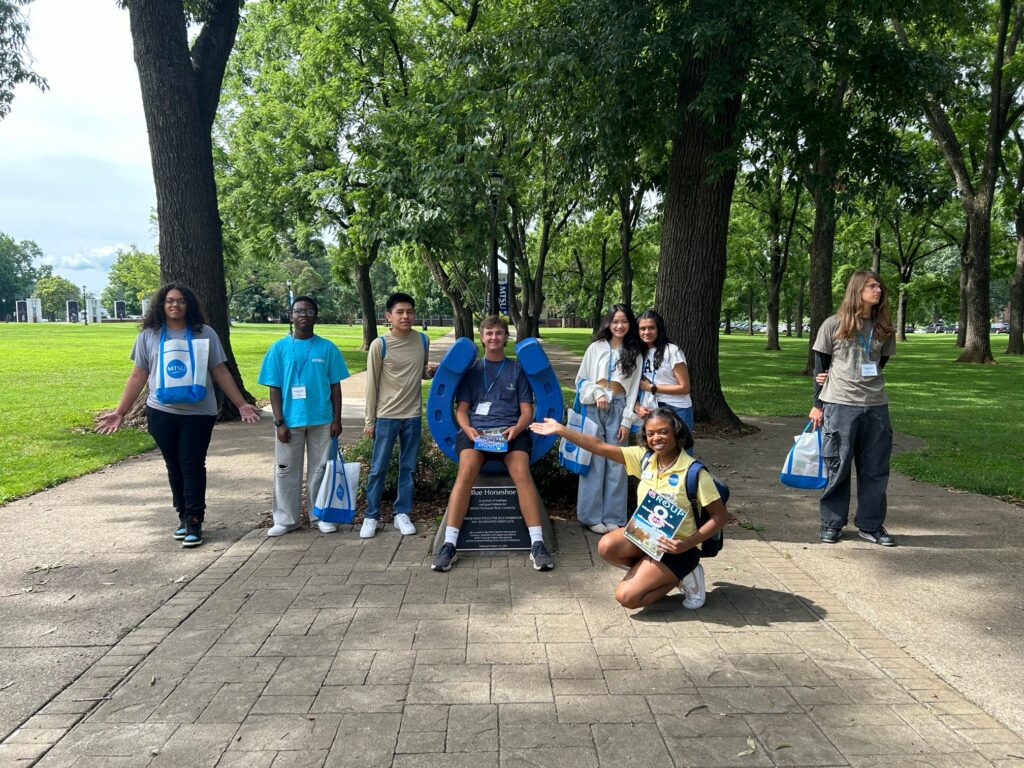 Students in Group 8 of orientation posing for a photo at the blue horseshoe at MTSU with their Student Orientation Assistant.