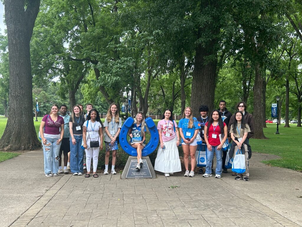 Students in Group 16 of orientation posing for a photo at the blue horseshoe at MTSU with their Student Orientation Assistant.
