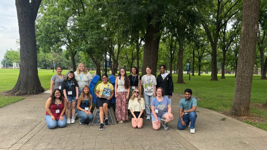 Students in Group 25 of orientation posing for a photo at the blue horseshoe at MTSU with their Student Orientation Assistant.