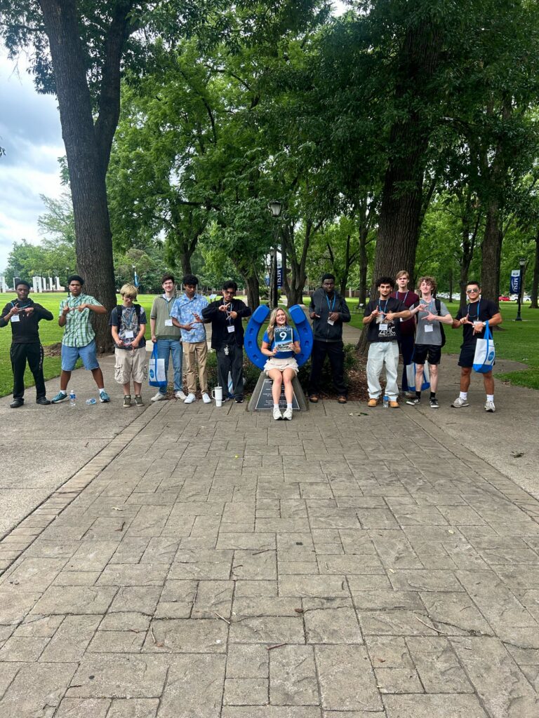Students in Group 9 of orientation posing for a photo at the blue horseshoe at MTSU with their Student Orientation Assistant.