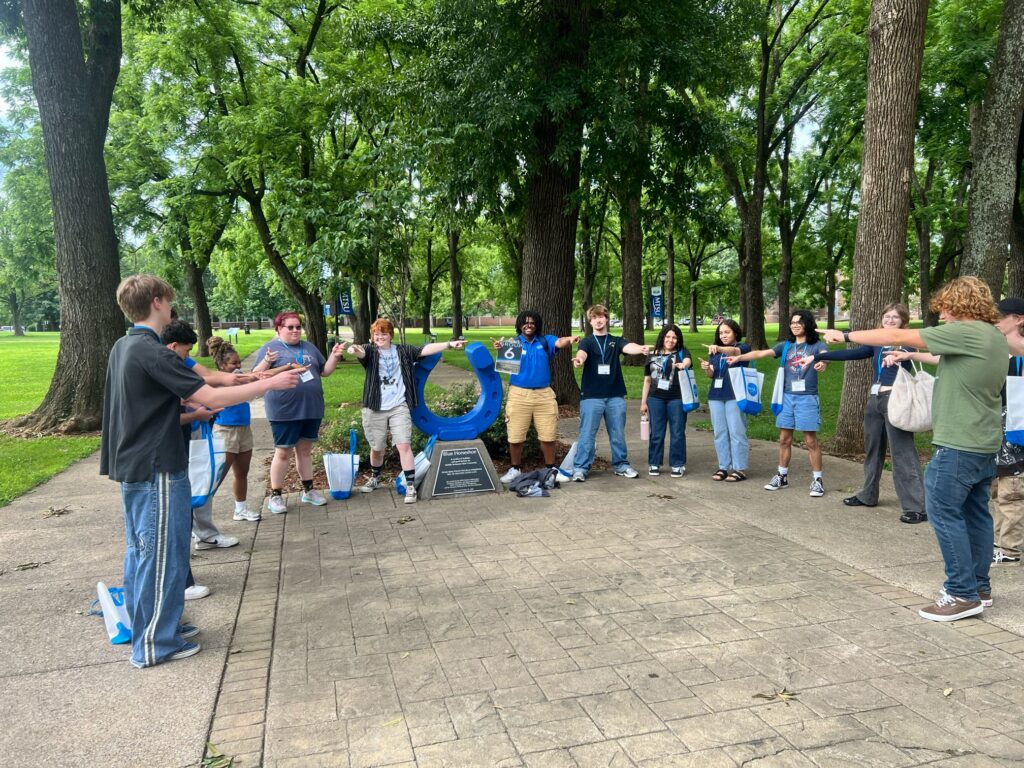 Students in Group 6 of orientation posing for a photo at the blue horseshoe at MTSU with their Student Orientation Assistant.