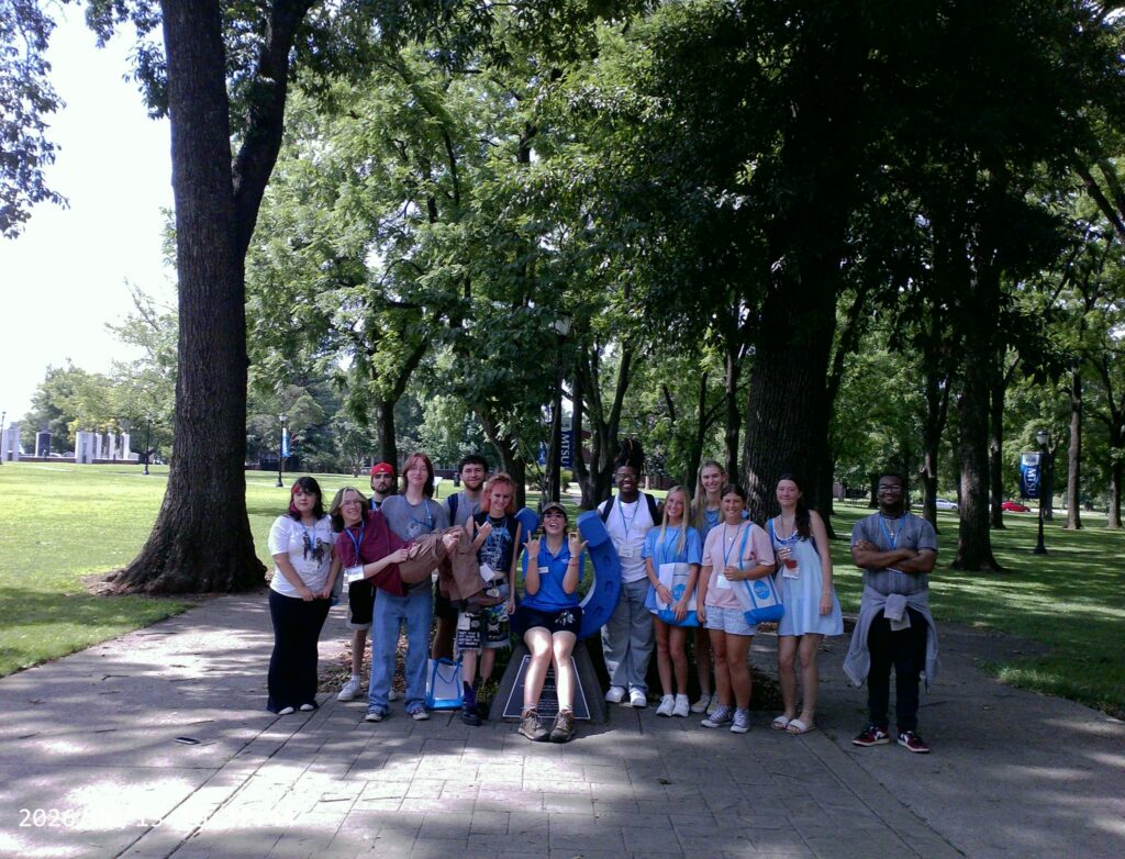 Students attending orientation posing for a photo at the blue horseshoe at MTSU with their Student Orientation Assistant.