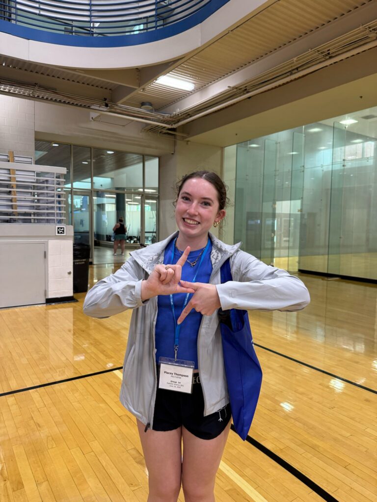 Student attending orientation forming a lightning symbol with their hands