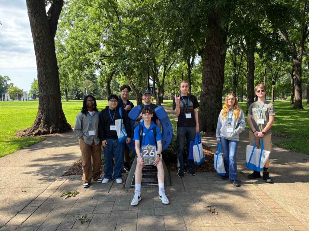 Students in Group 26 of orientation posing for a photo at the blue horseshoe at MTSU with their Student Orientation Assistant.