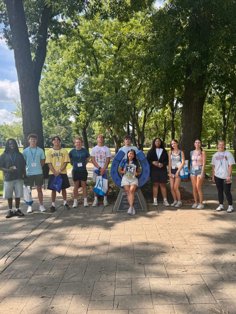Students in Group 14 of orientation posing for a photo at the blue horseshoe at MTSU with their Student Orientation Assistant.
