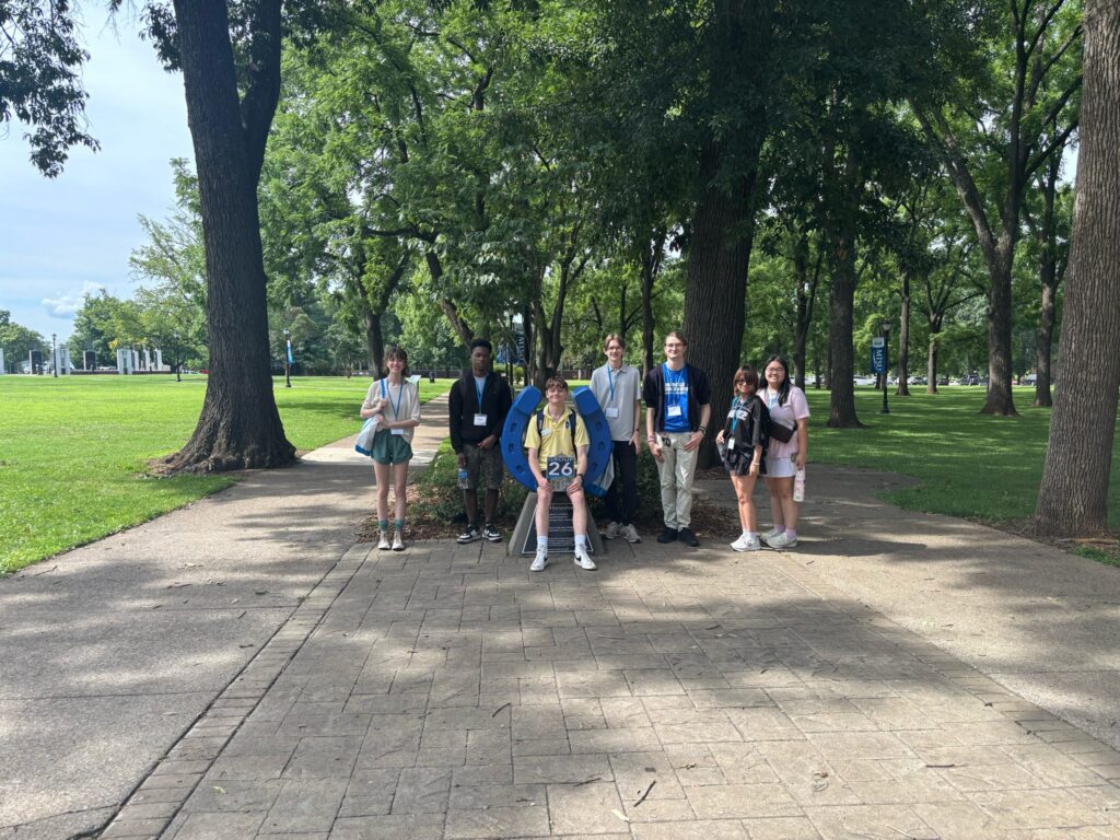 Students in Group 26 of orientation posing for a photo at the blue horseshoe at MTSU with their Student Orientation Assistant.