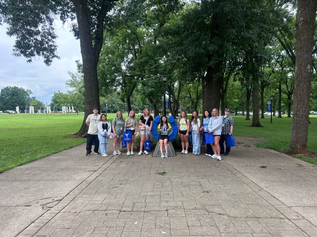 Students in Group 21 of orientation posing for a photo at the blue horseshoe at MTSU with their Student Orientation Assistant.