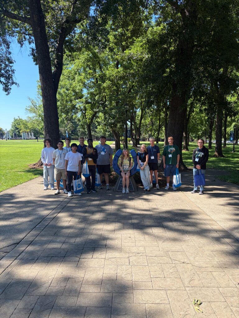 Students in Group 19 of orientation posing for a photo at the blue horseshoe at MTSU with their Student Orientation Assistant.