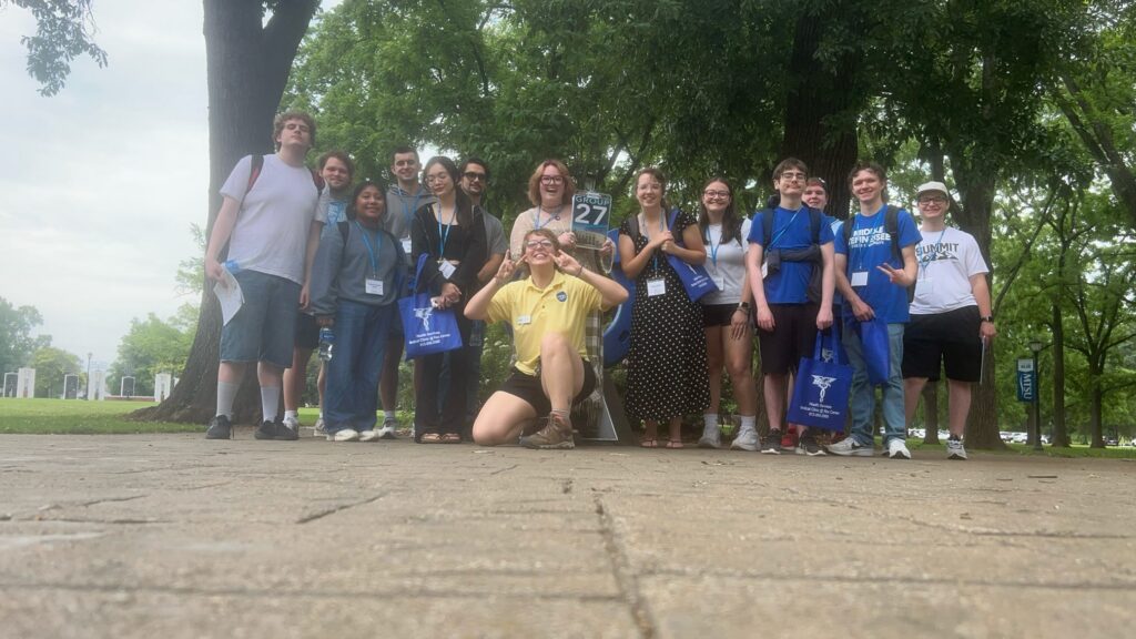 Students in Group 27 of orientation posing for a photo at the blue horseshoe at MTSU with their Student Orientation Assistant.