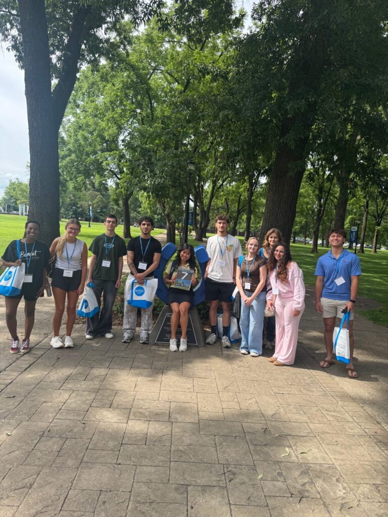 Students in Group 7 of orientation posing for a photo at the blue horseshoe at MTSU with their Student Orientation Assistant.