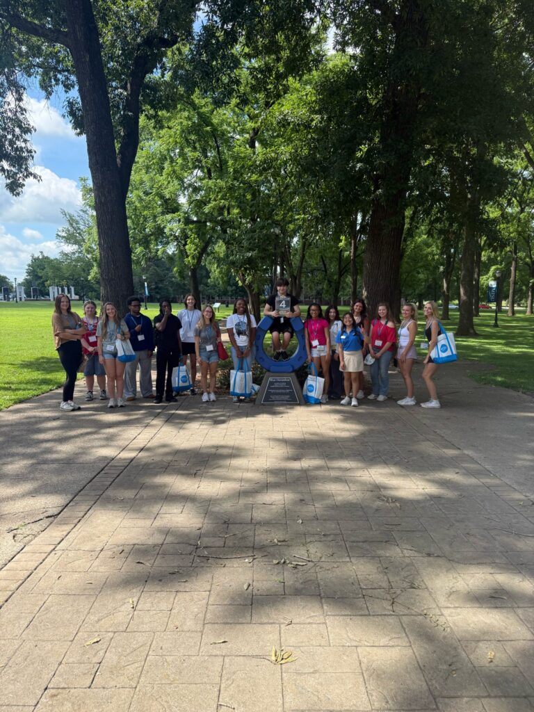 Students in Group 4 of orientation posing for a photo at the blue horseshoe at MTSU with their Student Orientation Assistant.