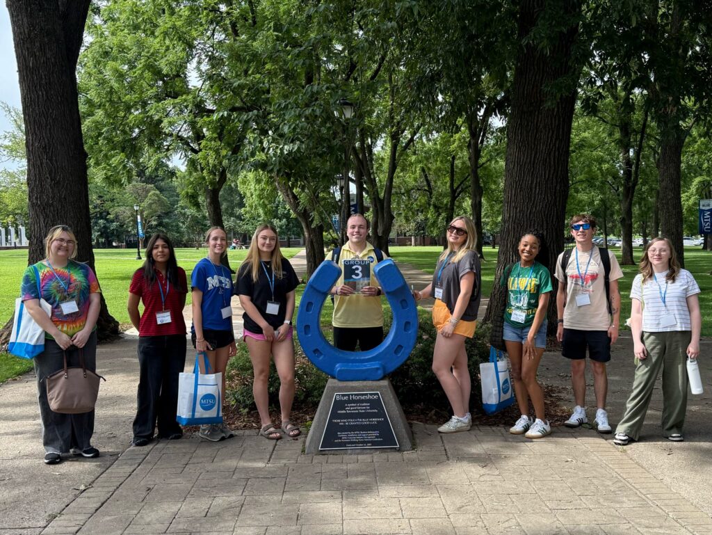 Students in Group 3 of orientation posing for a photo at the blue horseshoe at MTSU with their Student Orientation Assistant.
