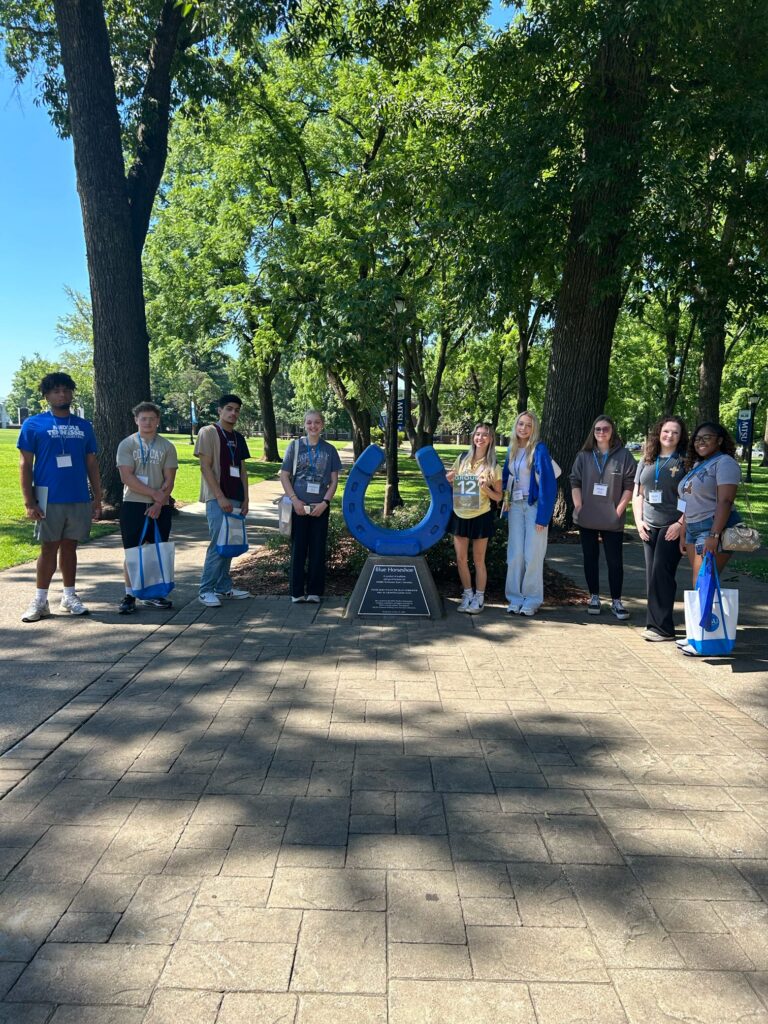 Students in Group 12 of orientation posing for a photo at the blue horseshoe at MTSU with their Student Orientation Assistant.