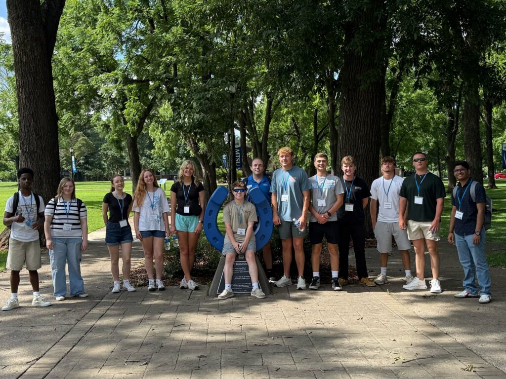 Students attending orientation posing for a photo at the blue horseshoe at MTSU with their Student Orientation Assistant.