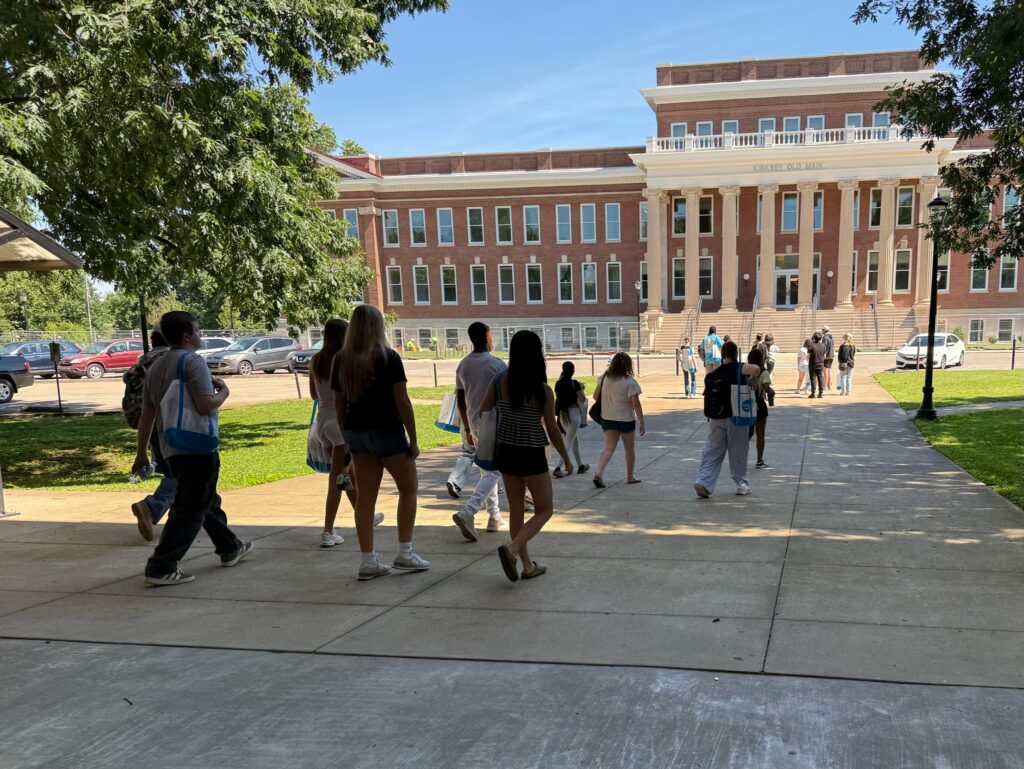 Students attending orientation walking towards the renovated Kirksey Old Main.