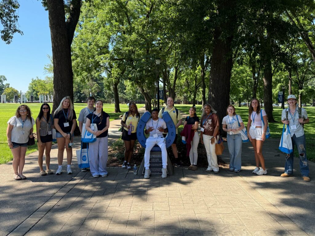 Students attending orientation posing for a photo at the blue horseshoe at MTSU with their Student Orientation Assistants.