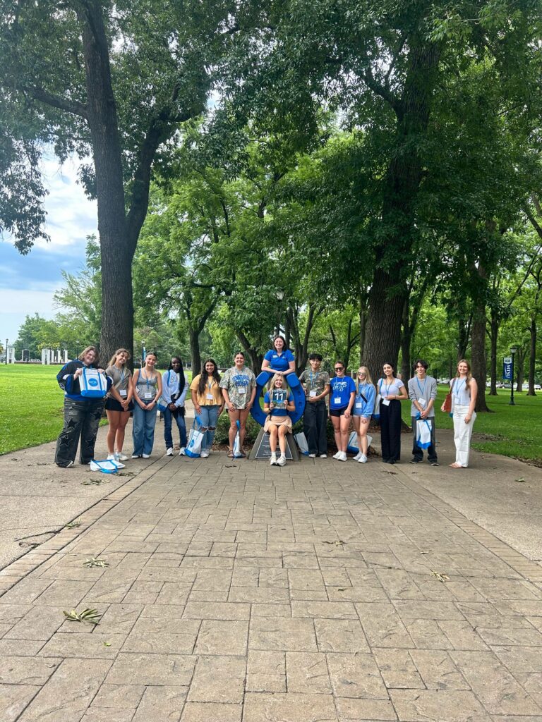 Students in Group 11 of orientation posing for a photo at the blue horseshoe at MTSU with their Student Orientation Assistant.