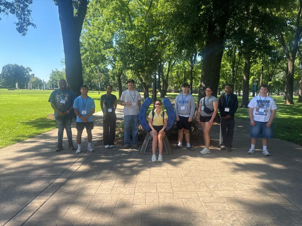 Students attending orientation posing for a photo at the blue horseshoe at MTSU with their Student Orientation Assistant.