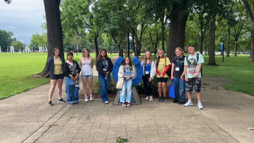 Students in Group 16 of orientation posing for a photo at the blue horseshoe at MTSU with their Student Orientation Assistant.